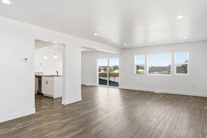 Expansive open living area with wood-finish flooring, recessed lighting, and multiple windows