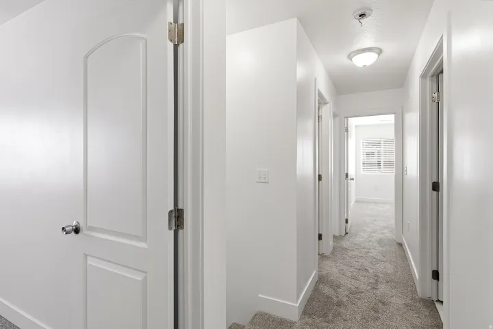 Hallway featuring flush-mount lighting, neutral wall paint, and gray carpet flooring