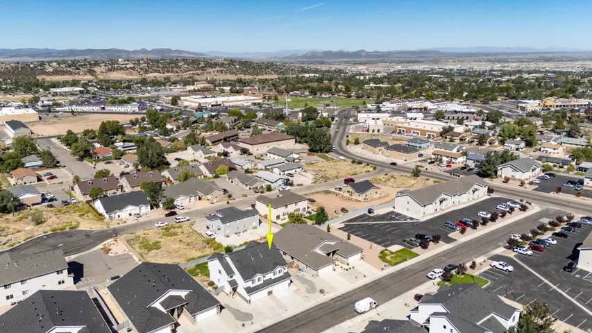Aerial perspective showcasing a residential dwelling with an attached garage and a surrounding neighborhood context