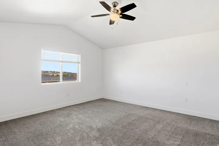 Vaulted ceiling with a contemporary ceiling fan, window with horizontal blinds, and carpeted flooring
