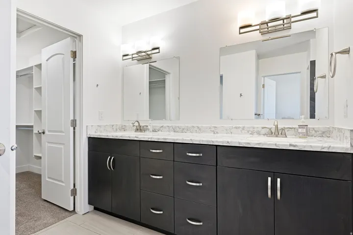 Dual vanity with stone-finish countertop, undermount sinks, and dark wood-finish cabinetry