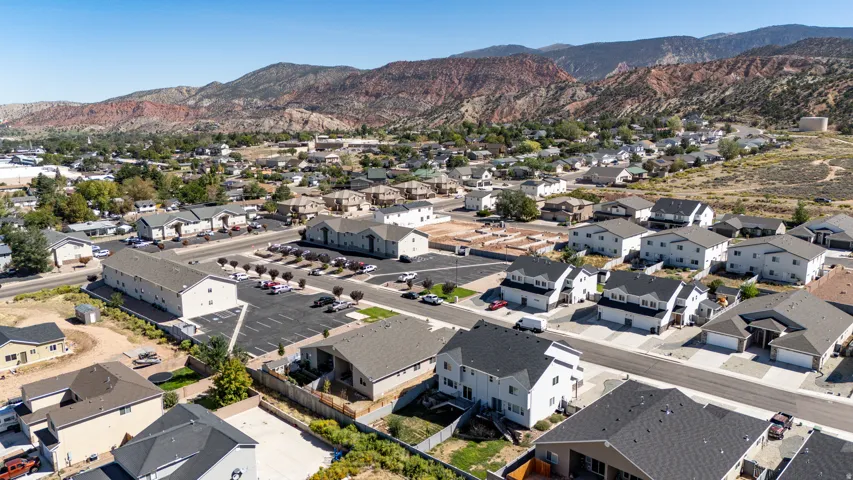 Residential development featuring various architectural styles, paved roadways, and landscaped common areas, set against a mountainous backdrop