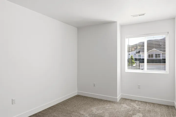 Neutral wall color with clean white trim, light-toned carpet, and a large window with horizontal blinds