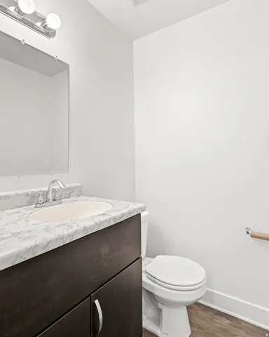 Bathroom featuring a dark wood-finish vanity with a white marbled countertop, an undermount sink, and a chrome faucet