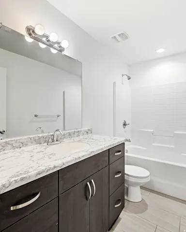 Dark wood-finish vanity with ample storage, integrated sink, and a stone-finish countertop