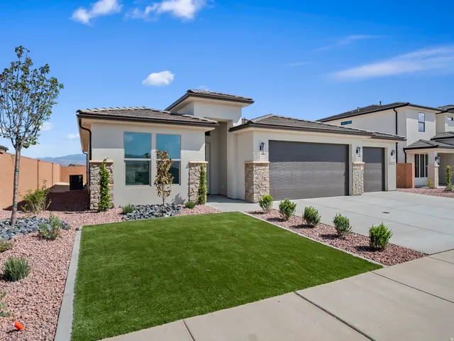 Stucco exterior with stone accents, 2-car garage, low-maintenance landscaping, artificial turf, and concrete driveway