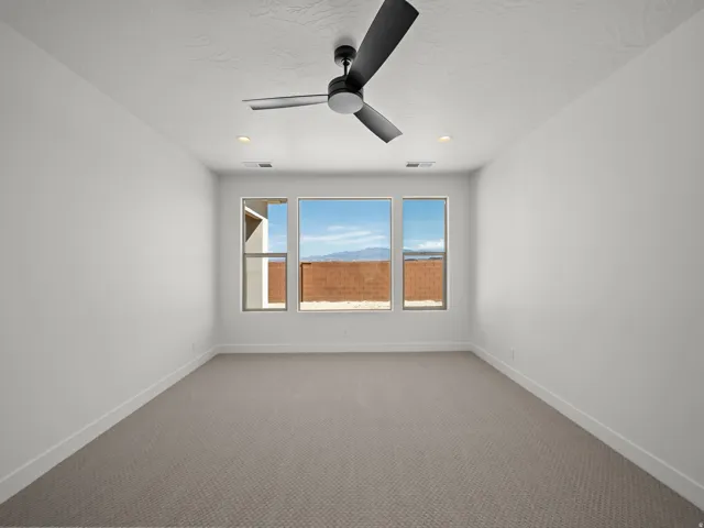 Neutral tone carpeting, multiple windows, recessed lighting, and a ceiling fan