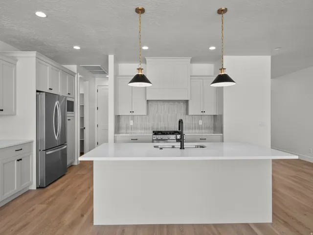 Kitchen featuring light-toned cabinetry, a spacious center island with a sink, stainless steel appliances, wood-finish flooring, and recessed lighting