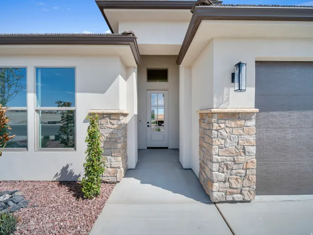 Stucco exterior with stone accents, covered entry, and a paneled garage door