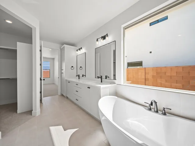 Primary bathroom featuring dual vanity with white cabinetry, rectangular vessel sinks, and matte black hardware