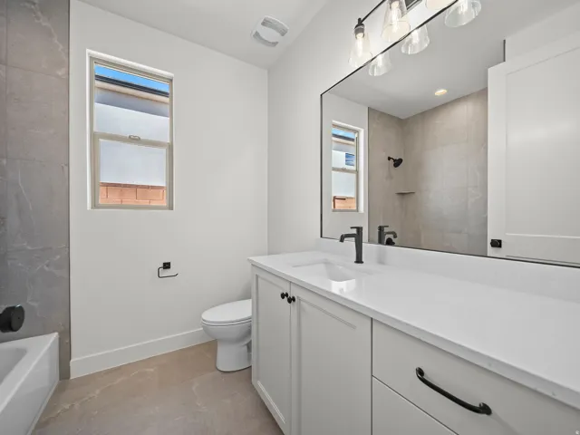 White vanity with an integrated sink, matte black faucet, and a large framed mirror