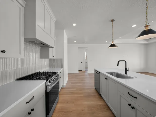 White cabinetry with panel detailing, light-toned countertops, and a vertical tile backsplash