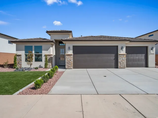 Stucco exterior with stone accents, a two-car garage, and a concrete driveway