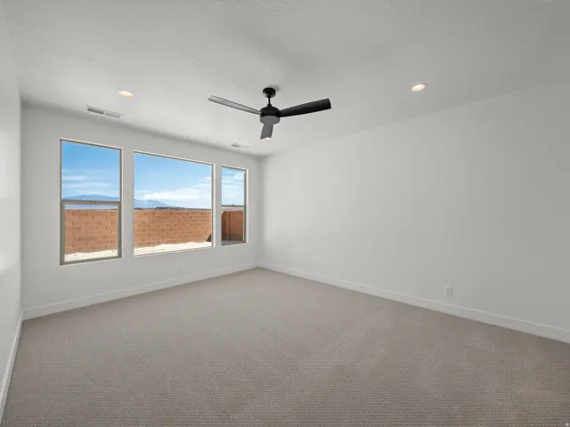 Carpeted interior space featuring a ceiling fan, recessed lighting, and multiple windows
