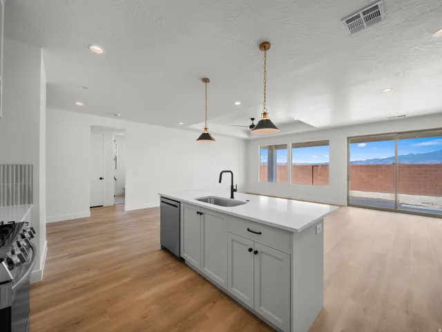 Kitchen island with a built-in sink, stainless steel dishwasher, and under-counter cabinetry
