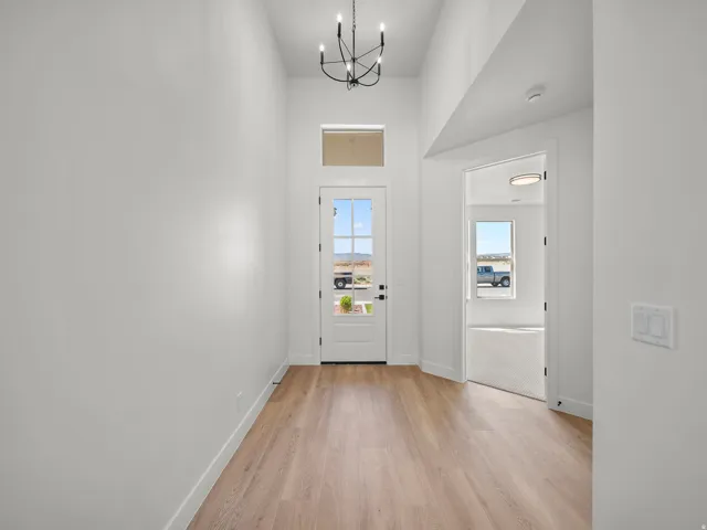 Entryway with wood-finish flooring, a contemporary chandelier, and a transom window above the front door