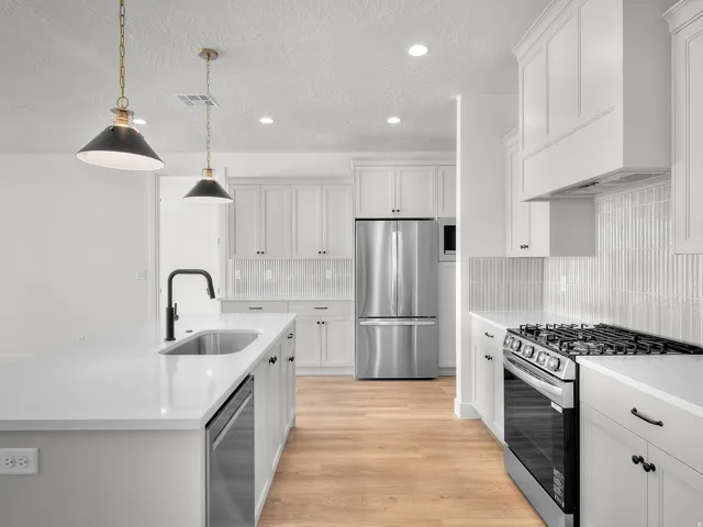Modern kitchen with a large island, stainless steel appliances, white cabinetry, a gas range, and wood-finish flooring