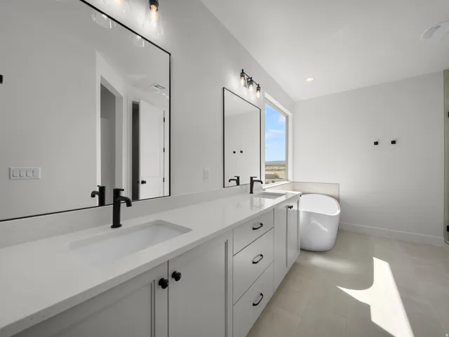 Dual vanity with stone-finish countertop, matte black fixtures, and integrated sinks