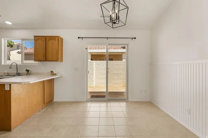 Kitchen area with wood cabinetry, light-toned countertop, and stainless-steel sink with a gooseneck faucet
