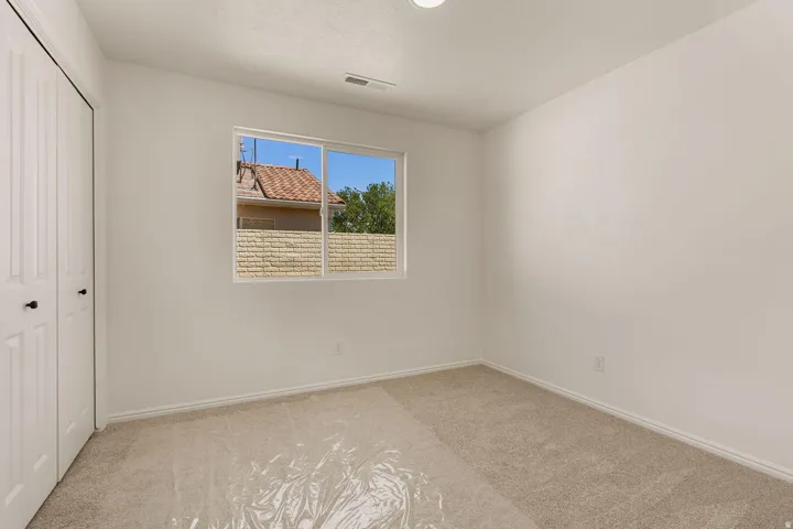 Carpeted room with white walls, a single window, and bi-fold closet doors