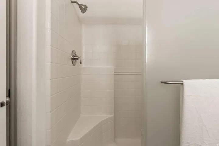 Shower with a built-in bench, white tile surround, and brushed nickel fixtures