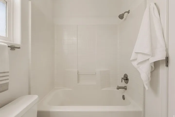 Bathtub with white subway tile surround, integrated shelving, and brushed nickel fixtures