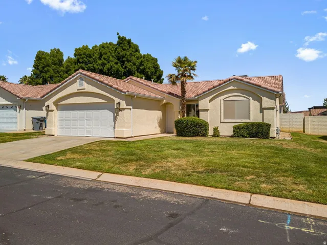 Stucco exterior with a tile roof, an arched window, a two-car garage, and a concrete driveway