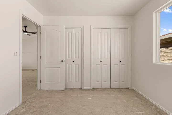 White interior walls, neutral carpet, white paneled doors, and a window with natural light