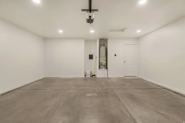 Spacious garage with concrete flooring, recessed lighting, and a water heater