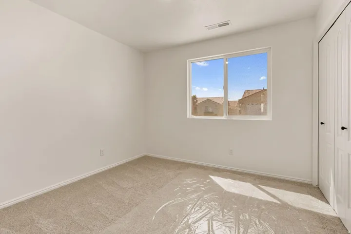 Neutral wall finishes, carpeted flooring, a double-pane window, and a bi-fold closet door