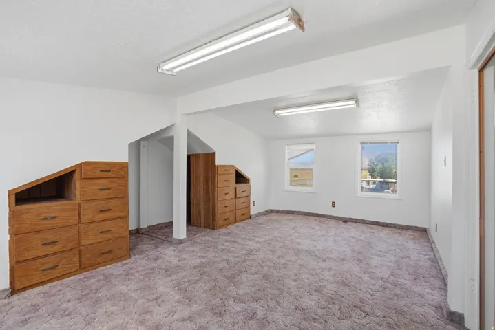 Carpeted floor, two windows, two built-in wood dressers, and recessed lighting