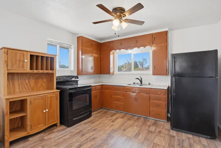 Kitchen featuring wood-finish flooring, white countertops, built-in cabinetry, dual-pane windows, and a ceiling fan