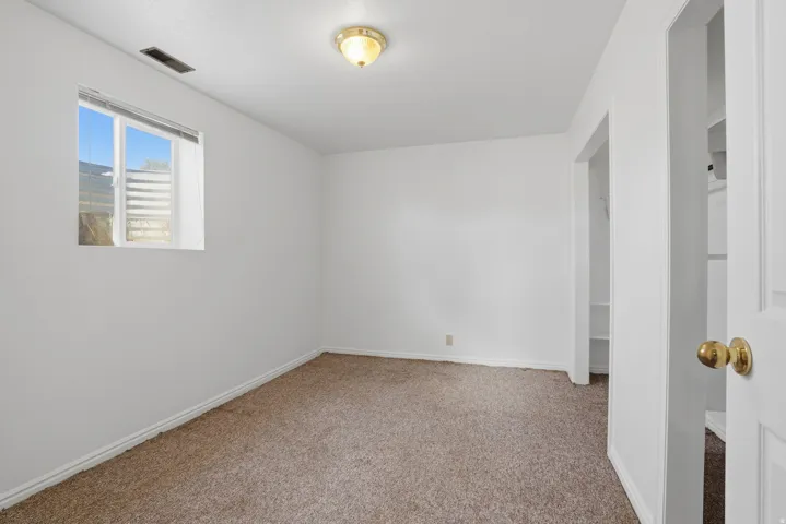 Carpeted room with white walls, a single window, and a ceiling-mounted light fixture