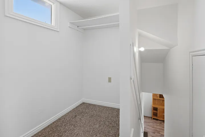 Carpeted alcove with a high window and built-in shelving
