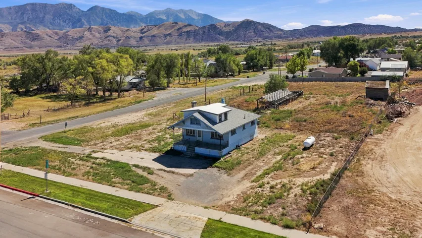 Expansive lot with a light blue exterior residence, featuring a covered porch and white trim