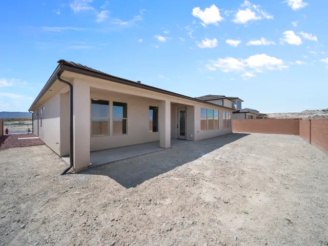 Expansive rear yard featuring a covered patio, stucco exterior, and a block perimeter wall