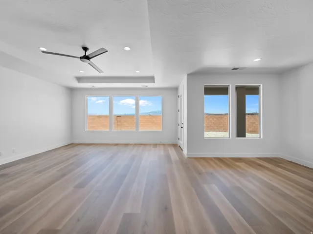 Expansive living area with wide plank wood-finish flooring, recessed lighting, and a modern ceiling fan