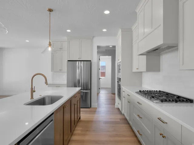 Kitchen featuring a large island with an undermount sink, brass-finish faucet, and integrated dishwasher