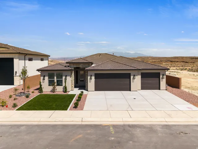 Contemporary stucco exterior with stone accents, a tile roof, a concrete driveway, and a two-car garage