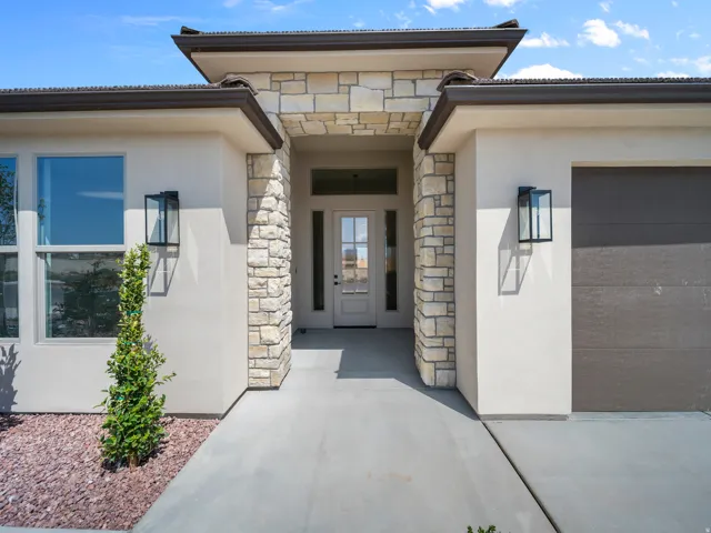 Stucco exterior with stone accents, a covered entry, and a glass-paneled front door