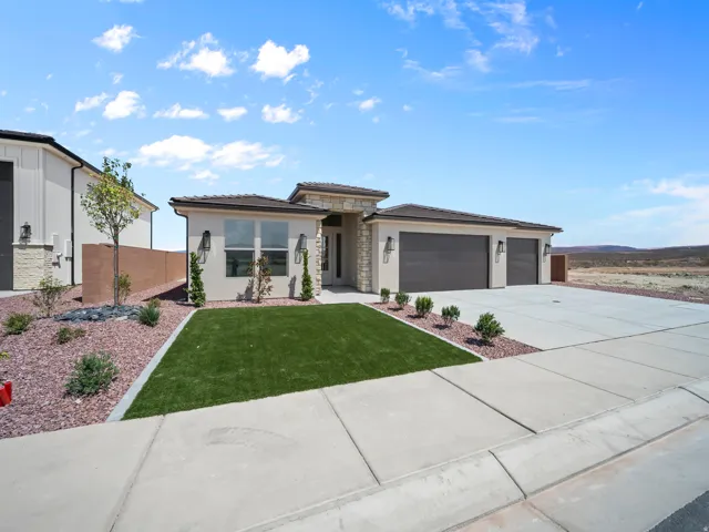 Stucco exterior with stone accents, concrete driveway, attached two-car garage, and a combination of artificial turf and gravel landscaping