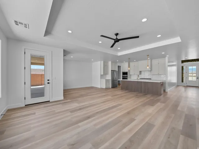Spacious open-concept layout with wood-finish flooring, recessed lighting, and tray ceilings