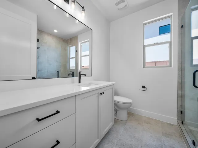 White vanity with quartz countertop, black hardware, and an undermount sink
