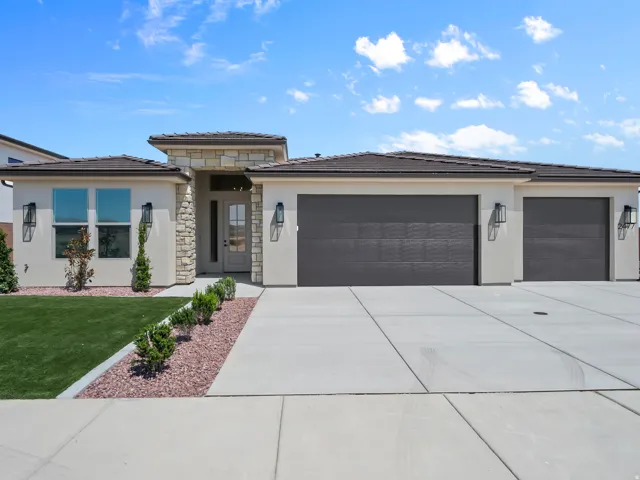 Stucco exterior with stone accents, a multi-car garage, concrete driveway, and low-maintenance landscaping