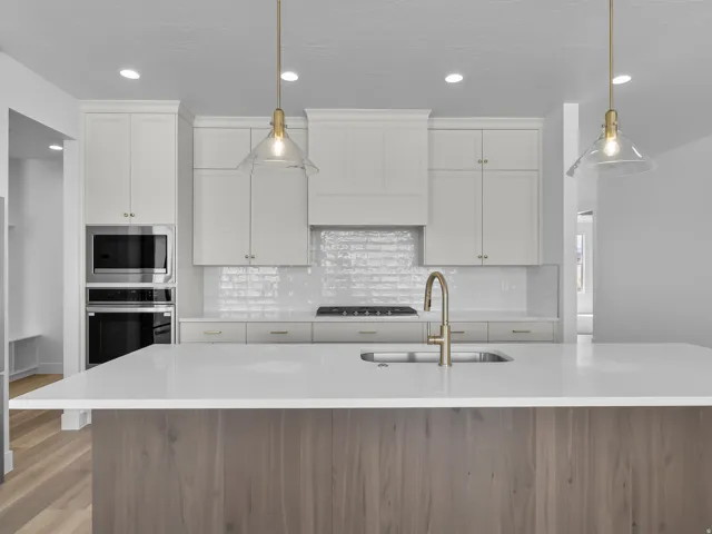Kitchen featuring a central island, white cabinetry, integrated stainless steel appliances, a white tile backsplash, and wood-finish flooring