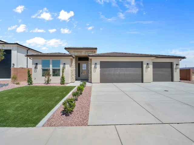 Stucco exterior with stone accents, two-car garage, concrete driveway, and front landscaping with artificial turf