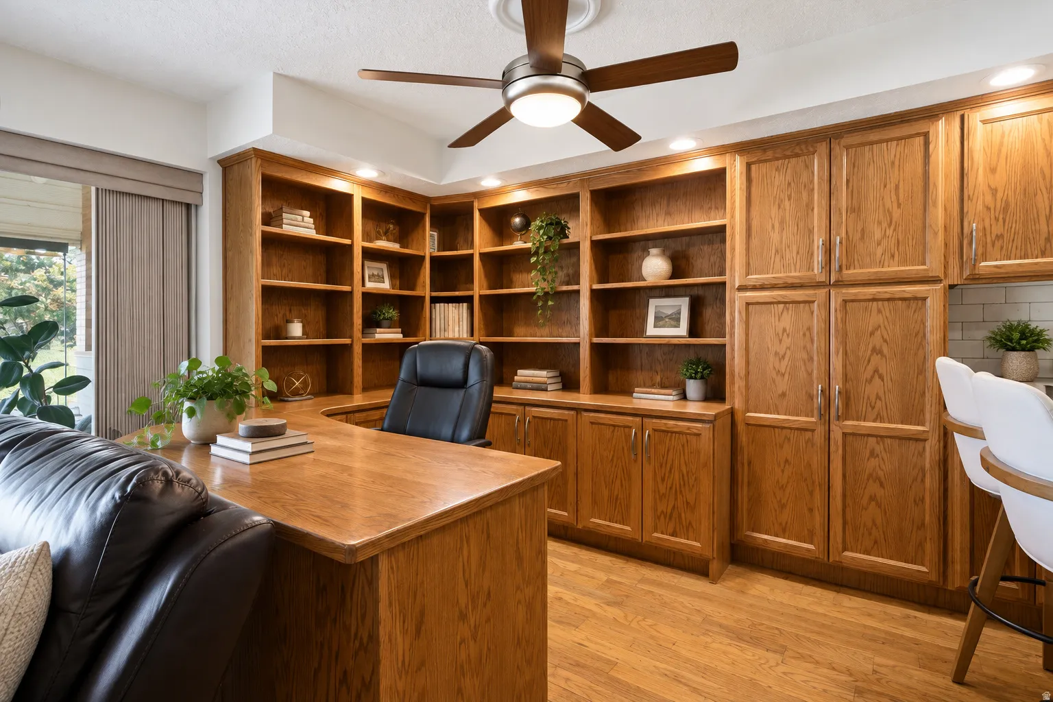 Built-in wood-finish shelving, wood-finish cabinetry, wood-finish flooring, recessed lighting, and a ceiling fan with integrated lighting
