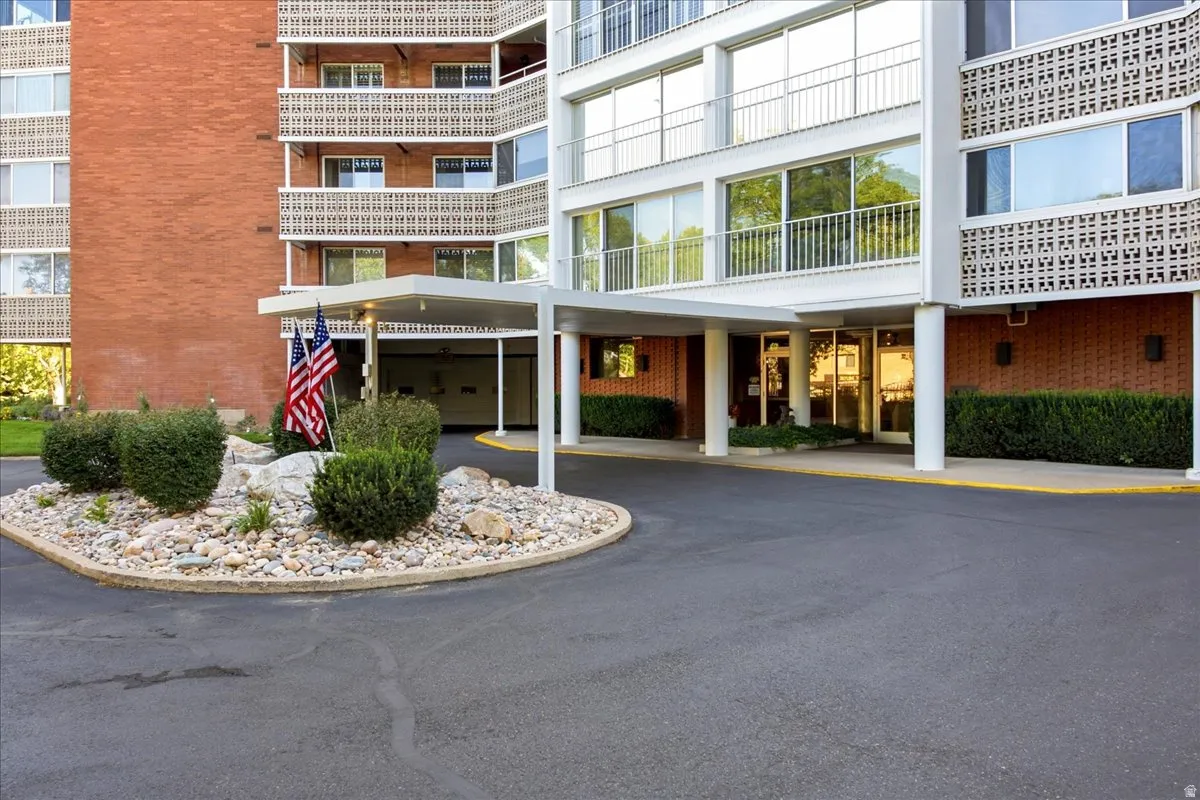 Building exterior with red brick and white-framed windows, a covered entrance, and a landscaped rock garden
