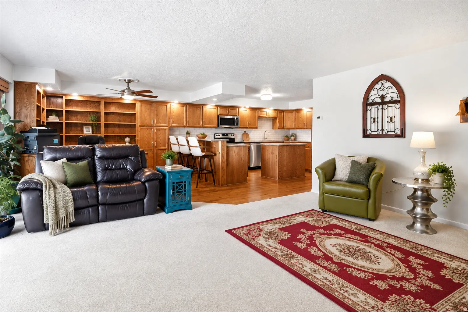 Open-concept living area featuring a kitchen with wood cabinetry, stainless steel appliances, and a breakfast bar