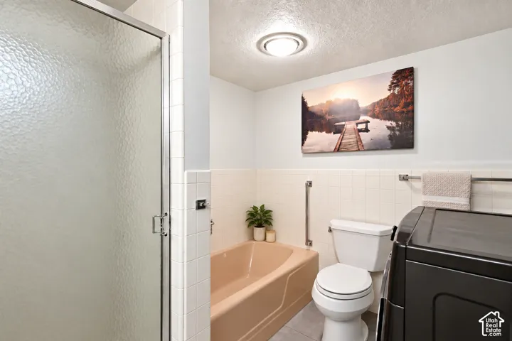White tiled walls with a peach-toned bathtub and a shower enclosure featuring textured glass